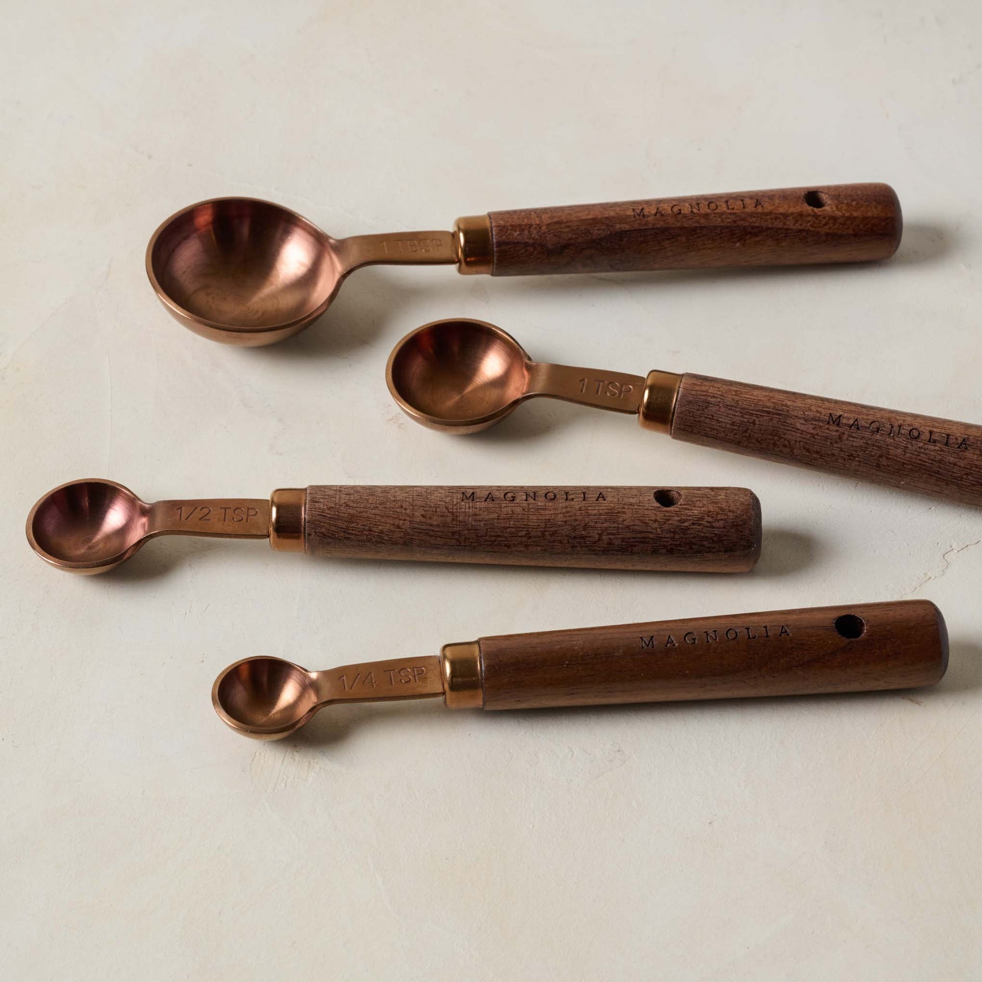 Walnut and Copper Measuring Spoons laid out separately, askew
