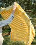Person holding a yellow and white striped outdoor blanket
