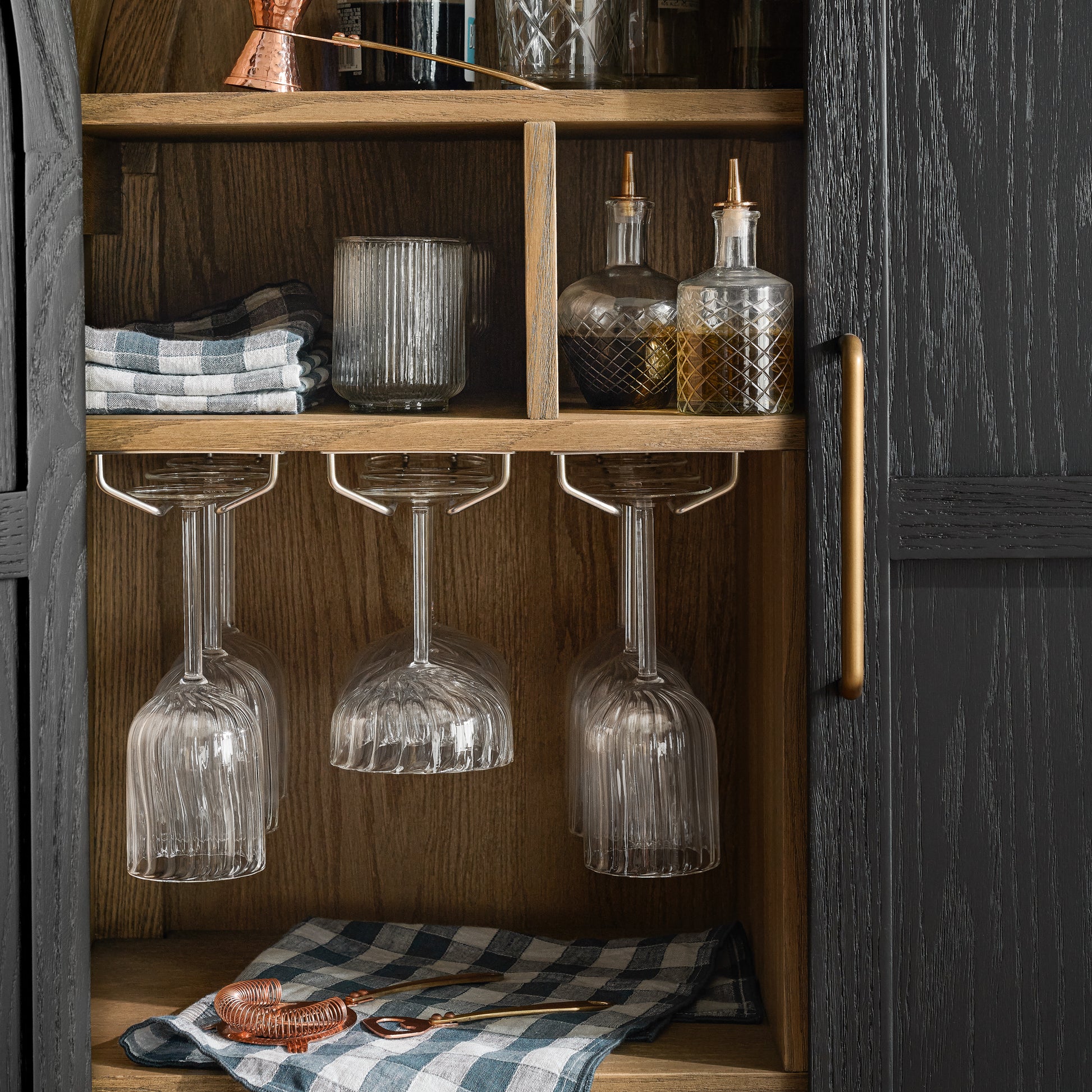 Inside of Matte Black Carraway Bar Cabinet shown styled with bar tools inside