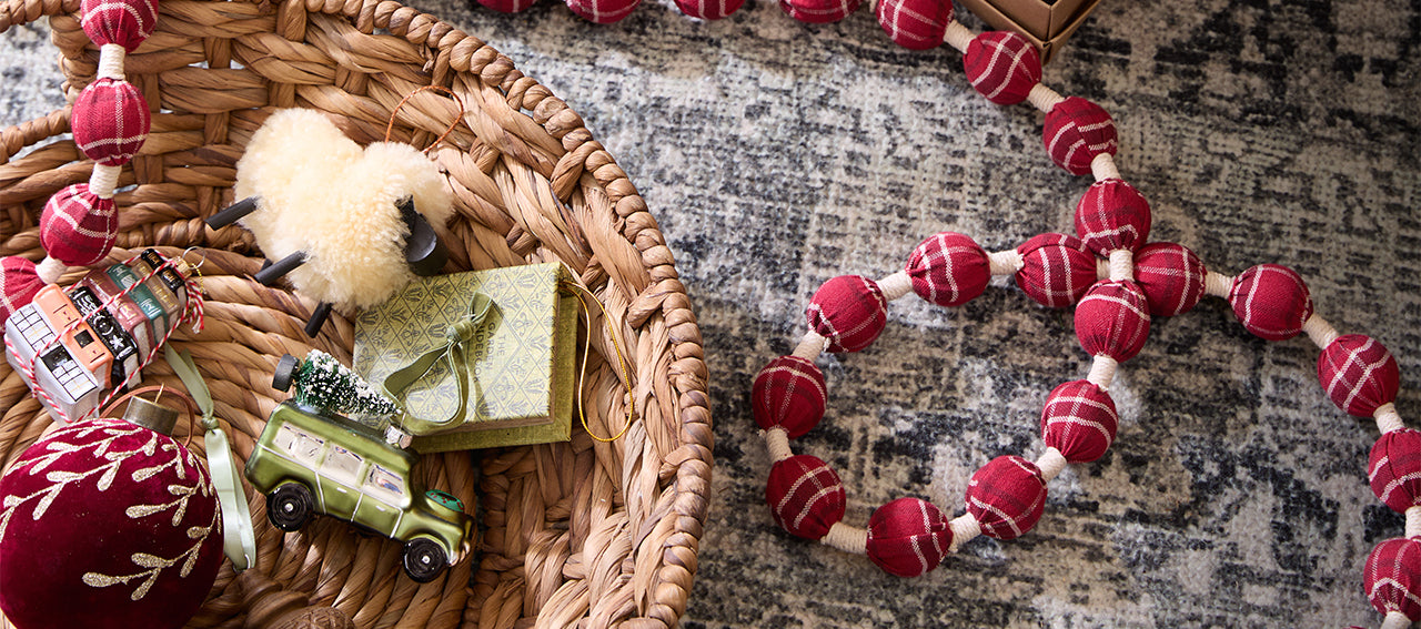 Decorative items including a small plush toy, wrapped gift, and red and white beaded necklace on a textured surface.