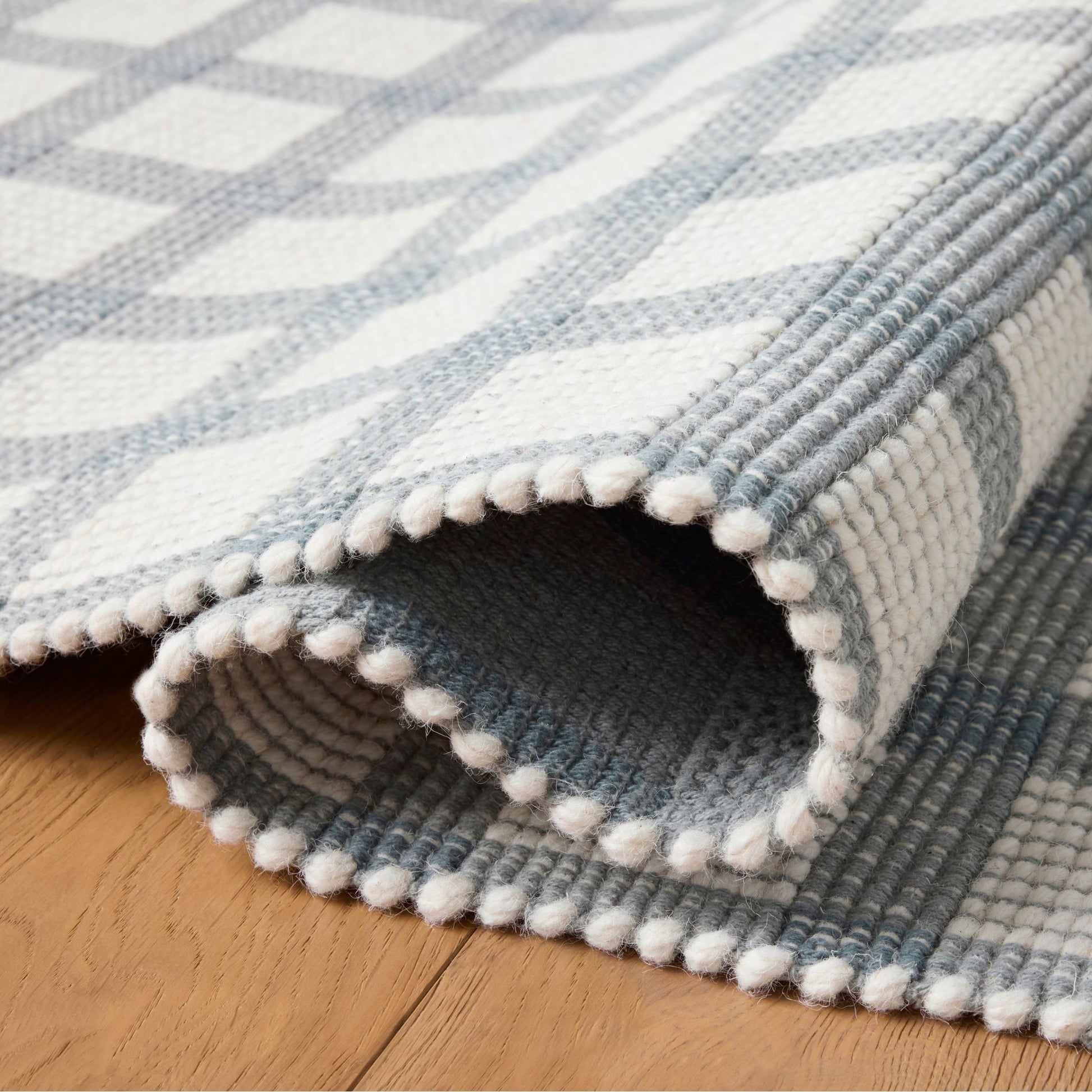 Ryder Blue Ivory Rug shown rolled/folded