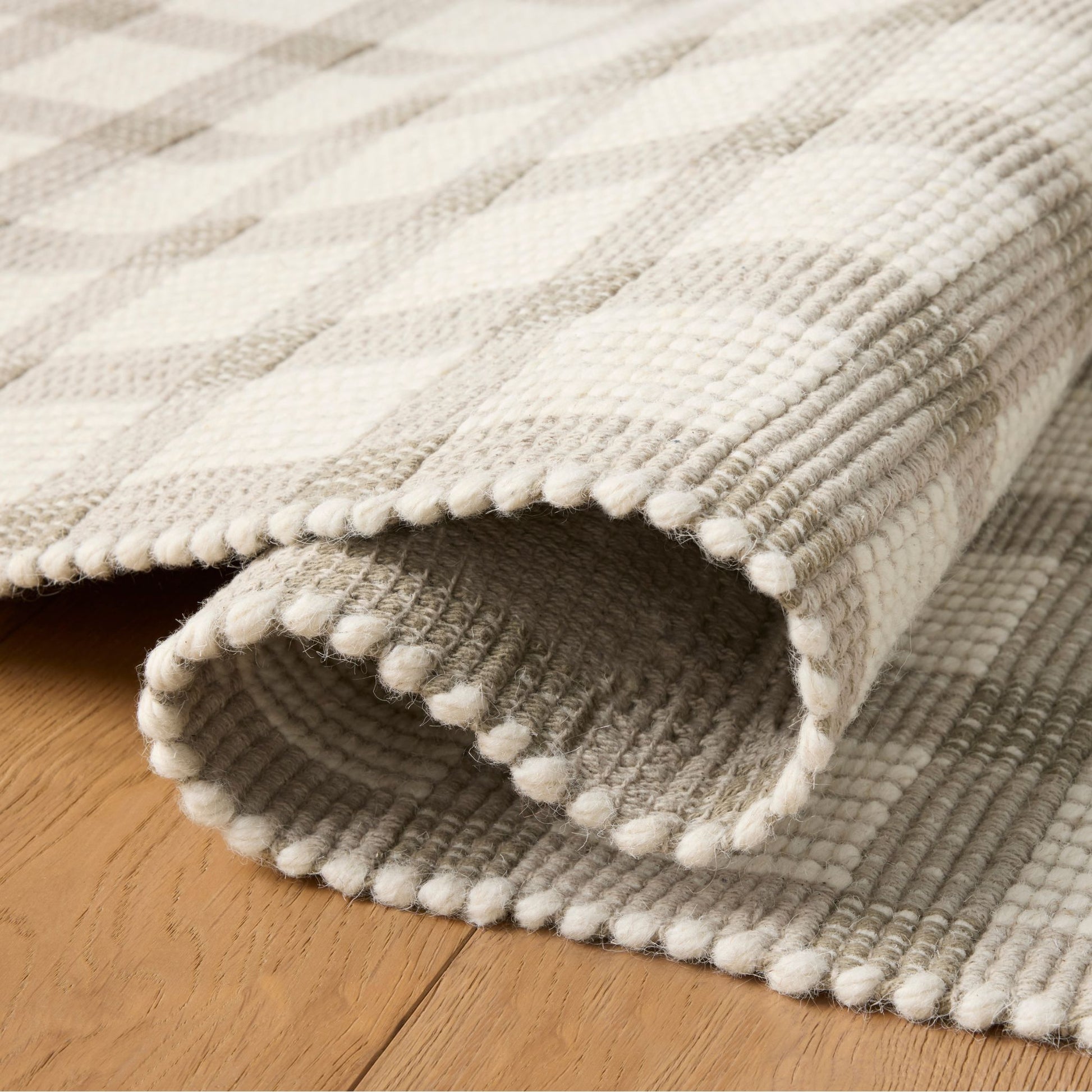 Ryder Stone Ivory Rug shown rolled/folded