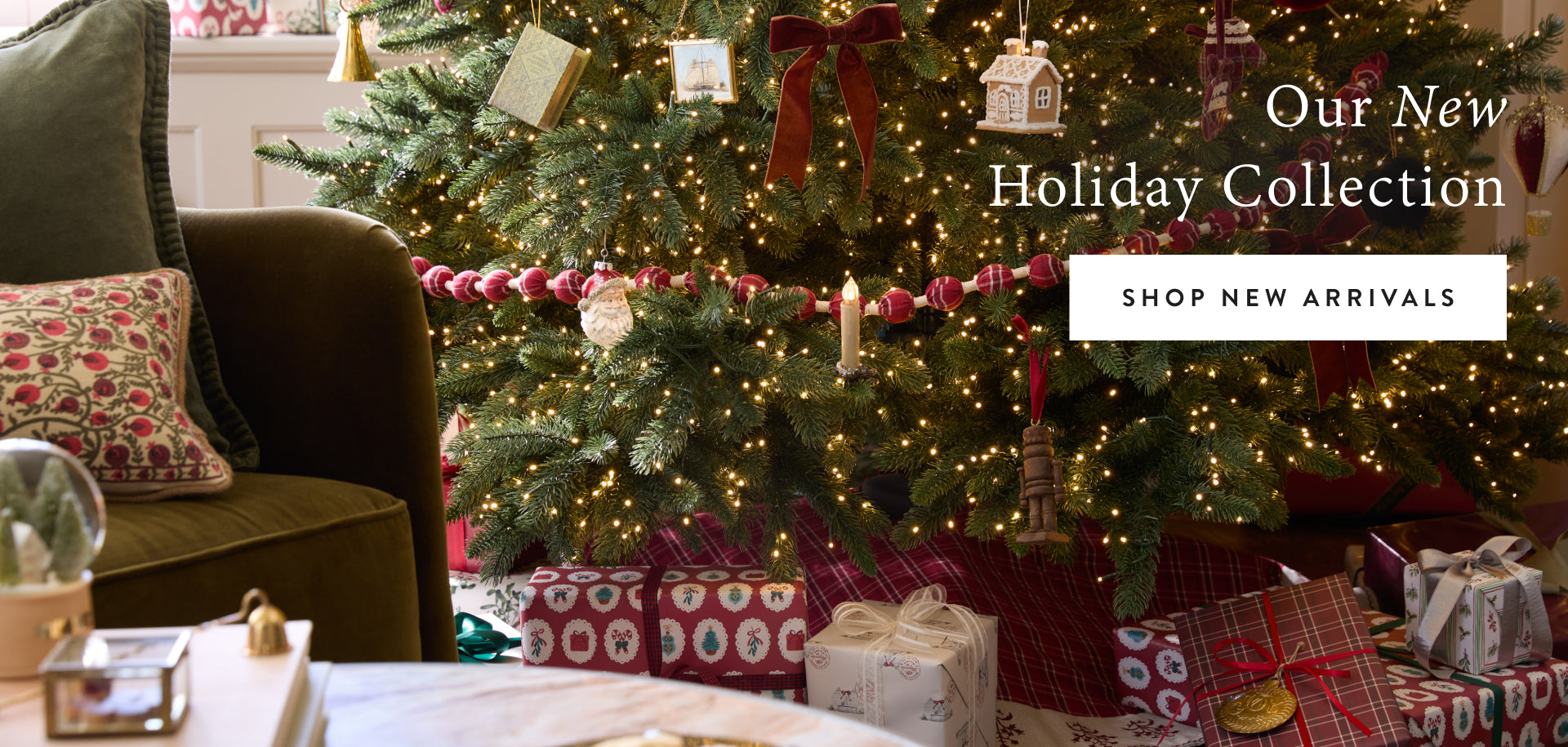 Decorated Christmas tree with presents and a couch in a living room setting, featuring 'Our New Holiday Collection' text.
