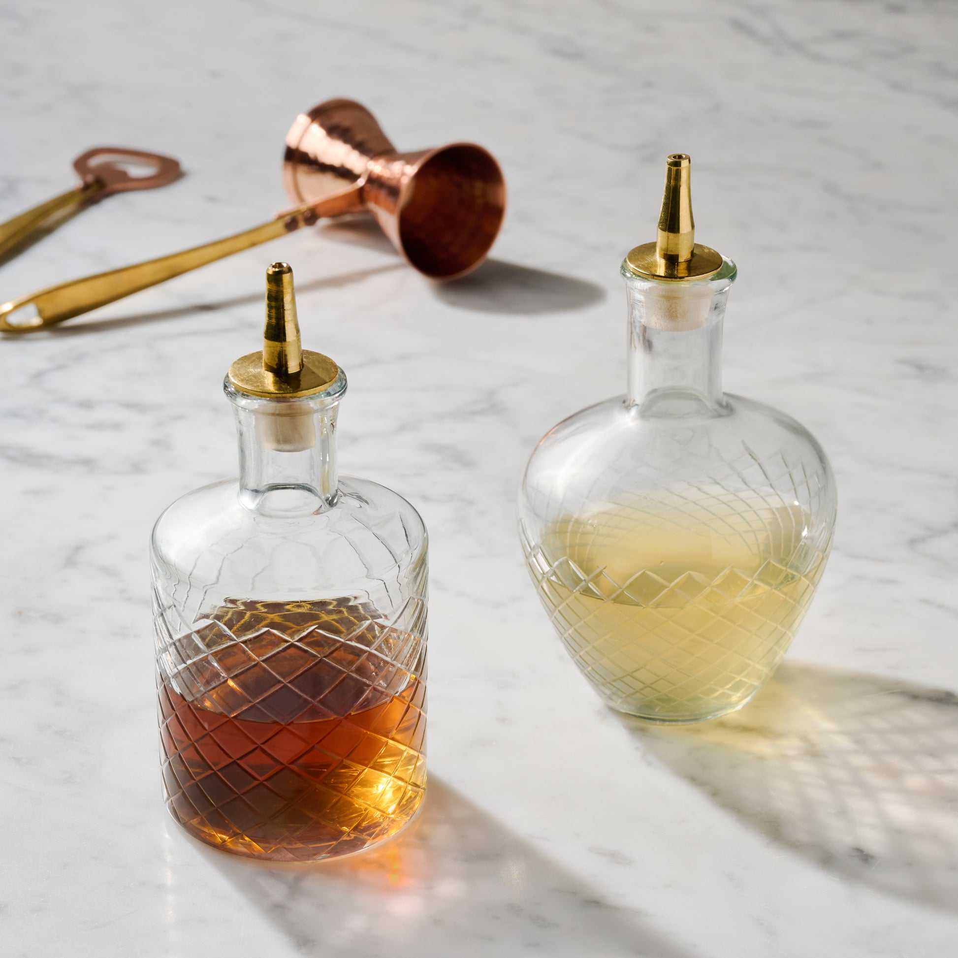 Vintage-Inspired Etched Glass Bottles shown with other bar tools nearby