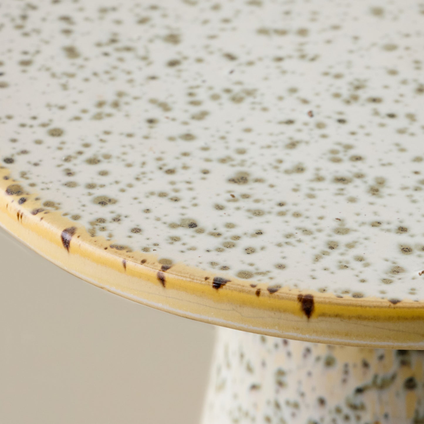 Close-up of a ceramic cake stand with speckled green glaze