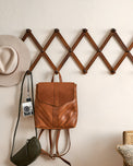 Accordion Wooden Wall Hook on a wall with accessories and handbags hanging