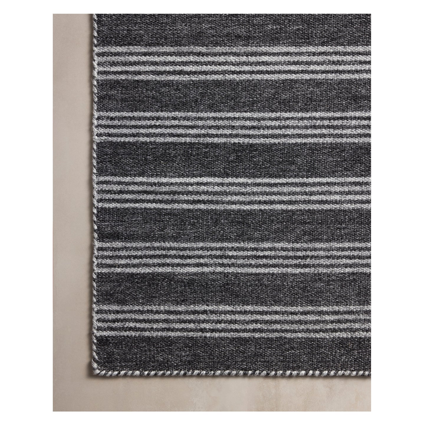 Charlie Charcoal Grey Rug on a beige floor