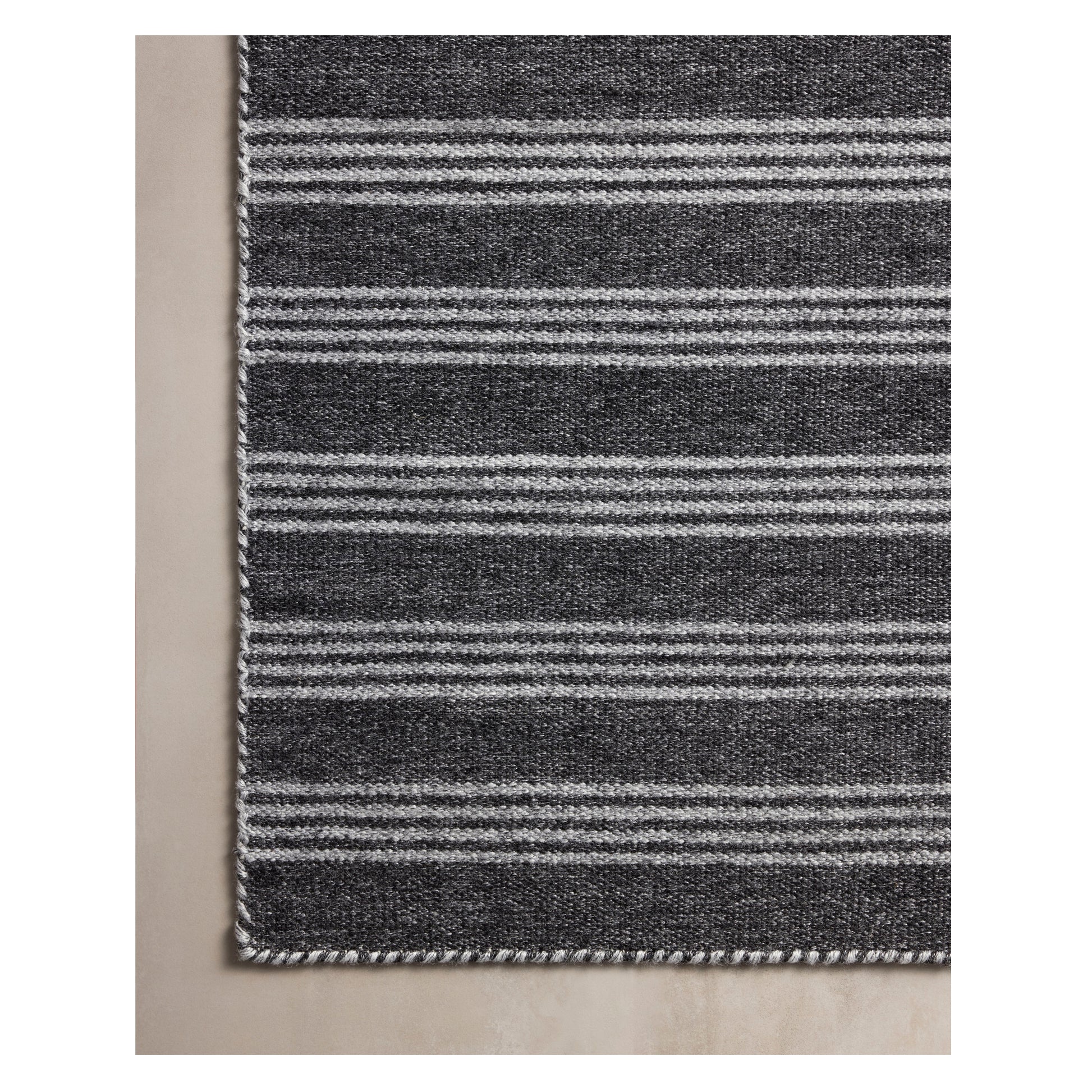 Charlie Charcoal Grey Rug on a beige floor