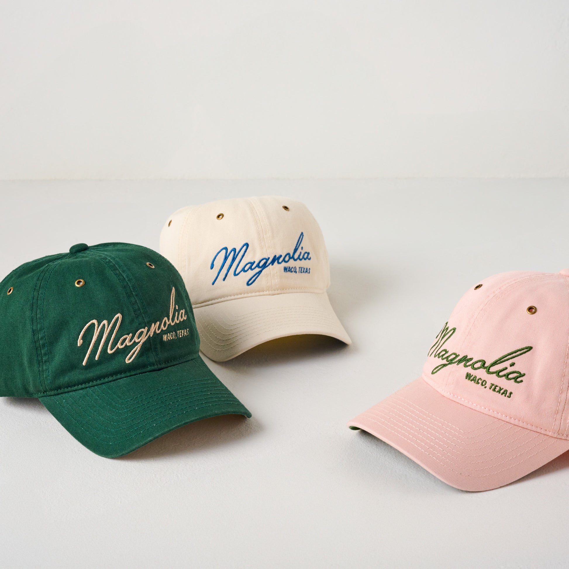 Magnolia Embroidered Script Cream Hat shown with green and pink hats