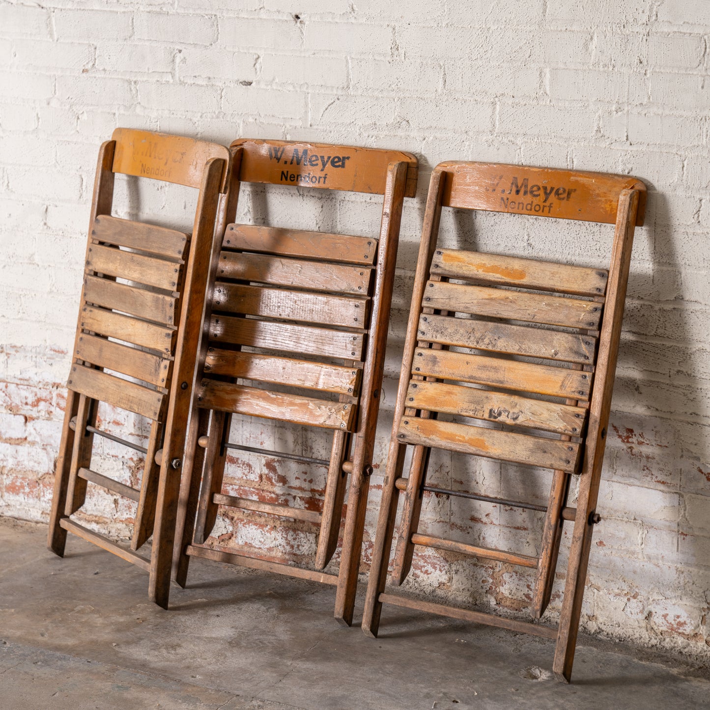 Vintage Wooden German Folding Chairs shown leaning up against wall