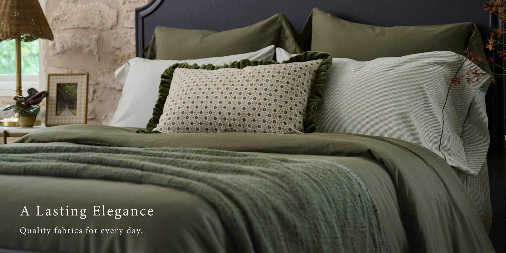 Bed with green bedding and decorative pillows in a cozy bedroom setting. Shop Bedding.