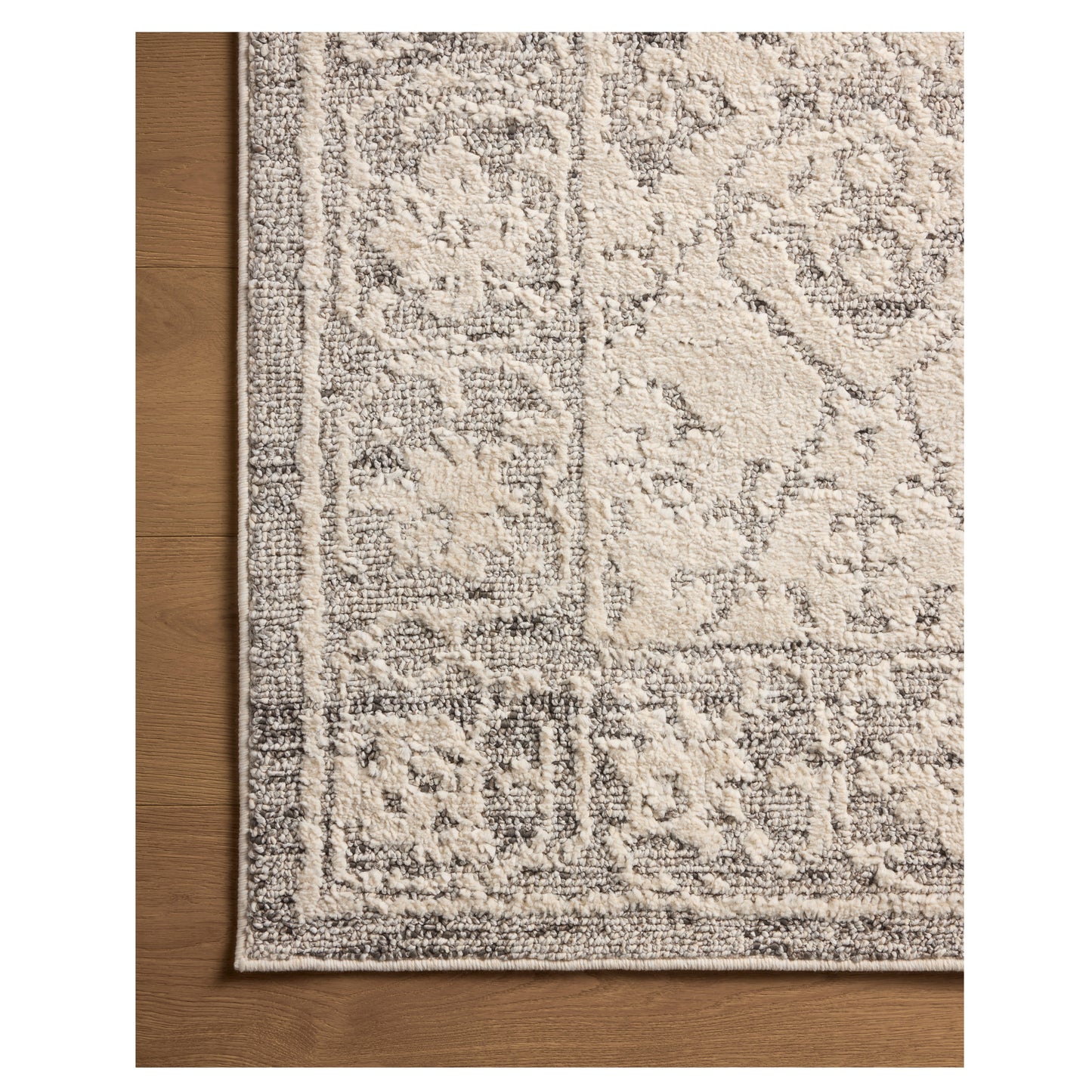 Gigi Ivory Stone Rug close up of corner of rug on wood floor