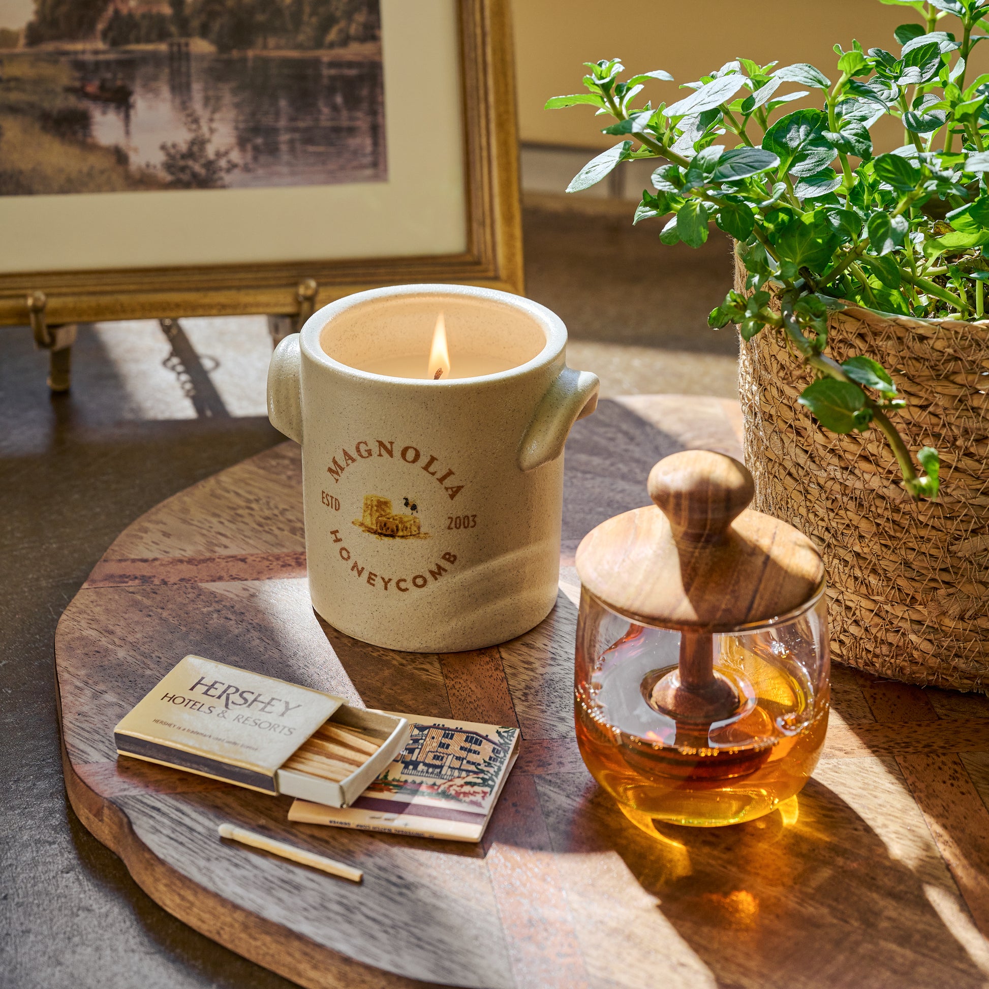 Antiqued Wood Round Serving Board with a candle, honey dipper, and potted plant on top