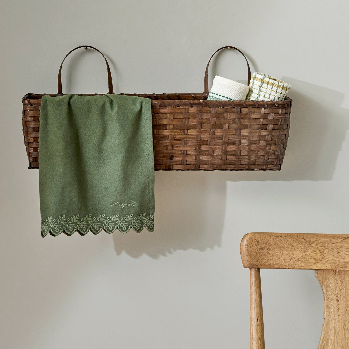 Magnolia Embroidered Scalloped Edge Tea Towel shown in basket on wall
