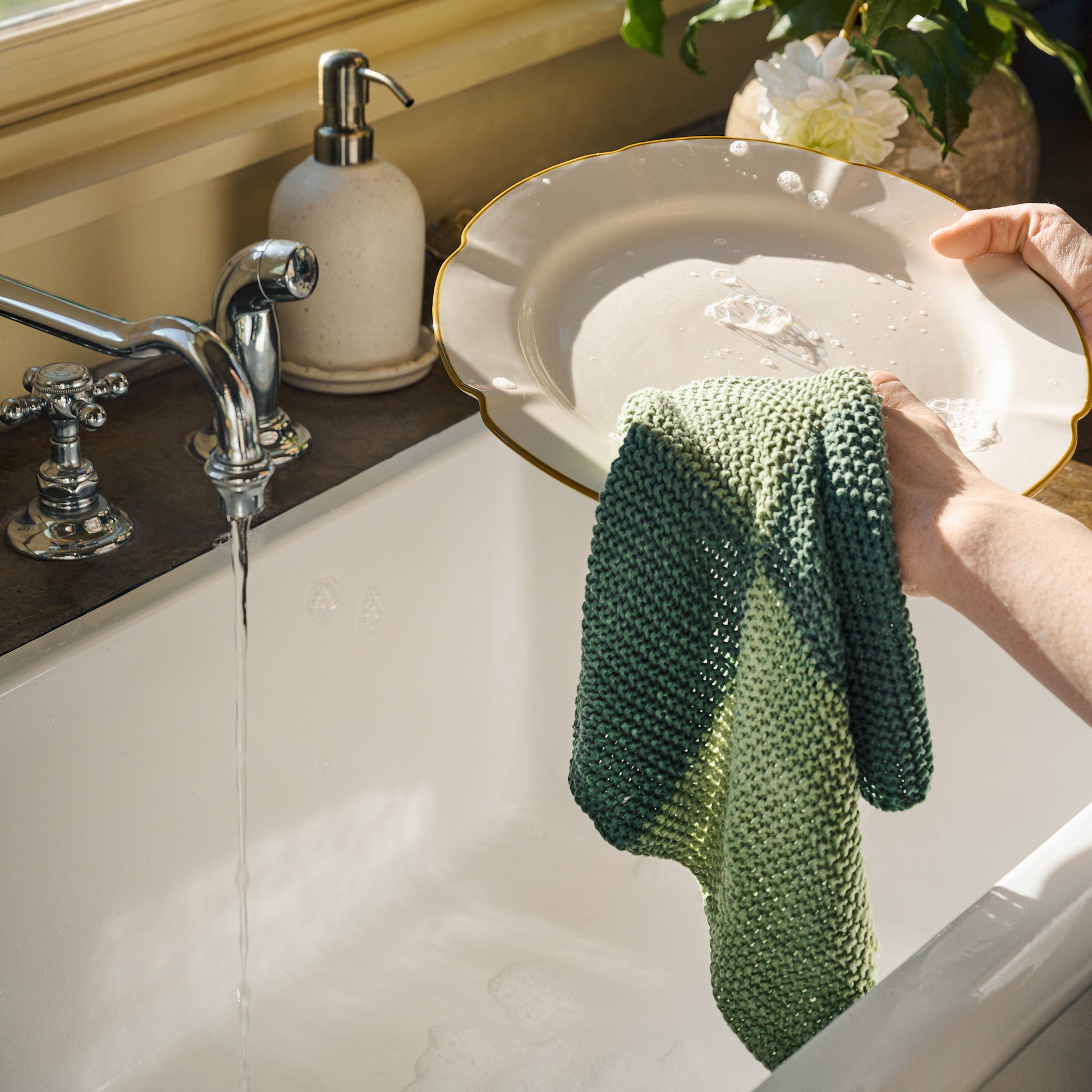 two hands wash a Luna Scalloped Plate with a wash cloth