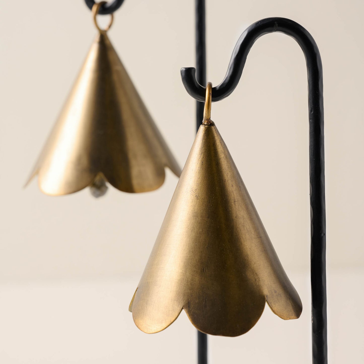 close up view of brass scallop bells hanging from black metal stand