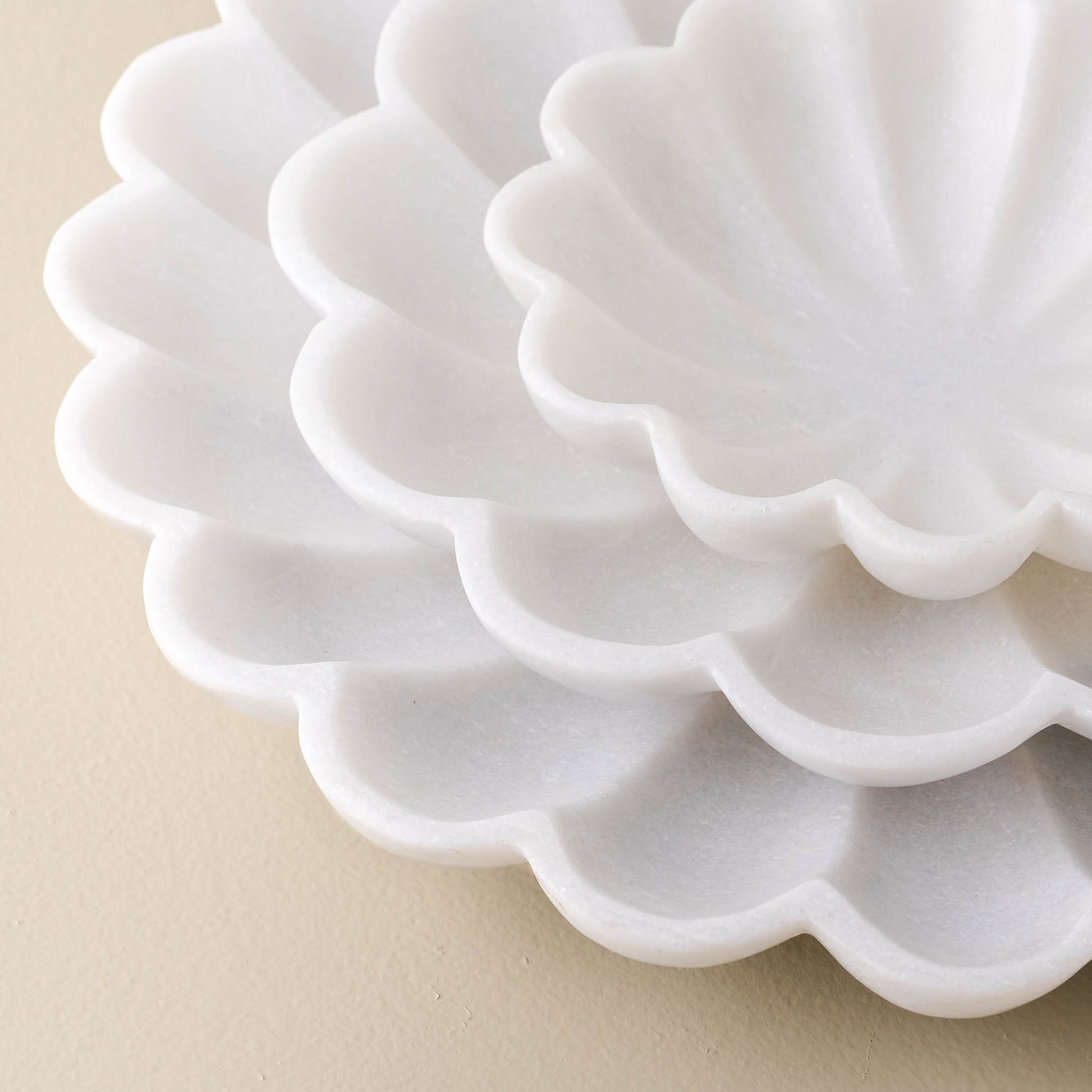 stacked detail view of three white marble scalloped accent bowls