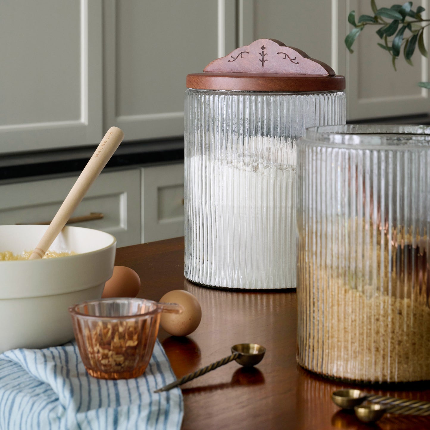Small and Large Antiqued Wood Ribbed Glass Canisters shown on countertop with bakeware