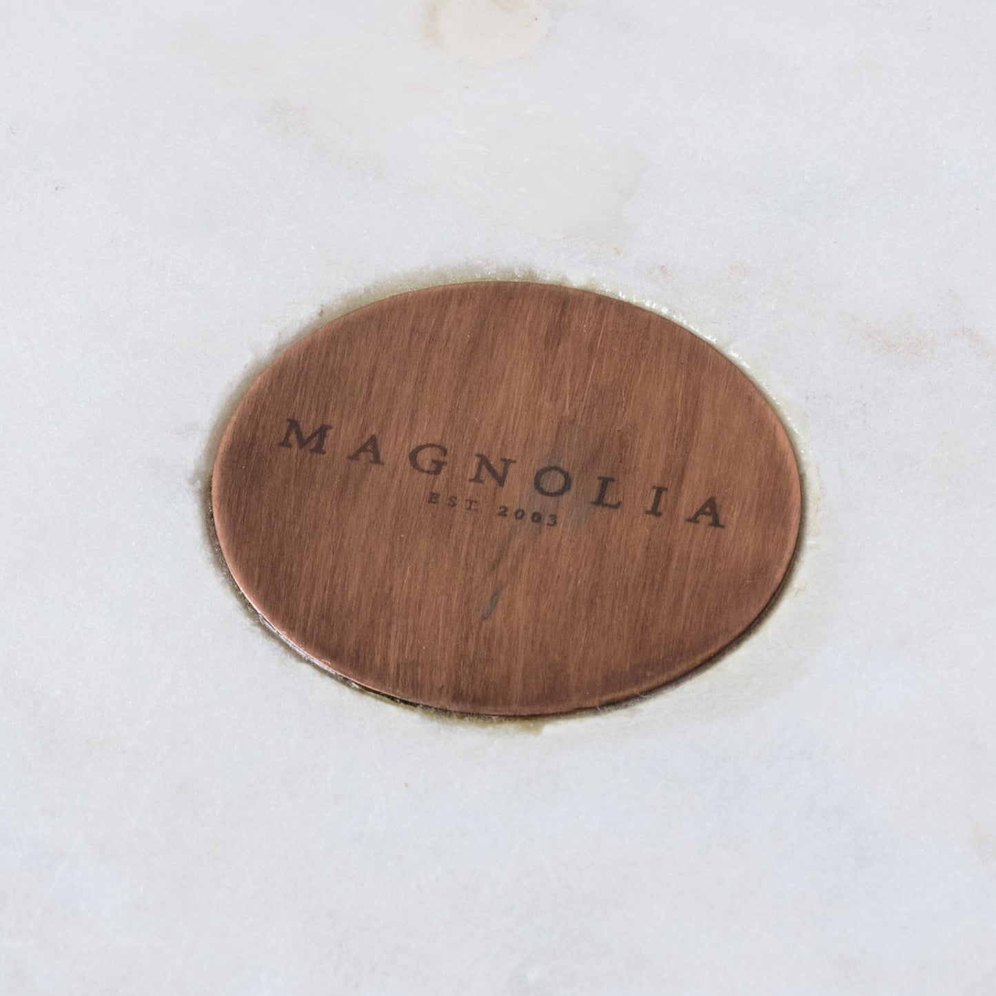 Marble and Copper Cake Stand close up of magnolia logo on center of marble