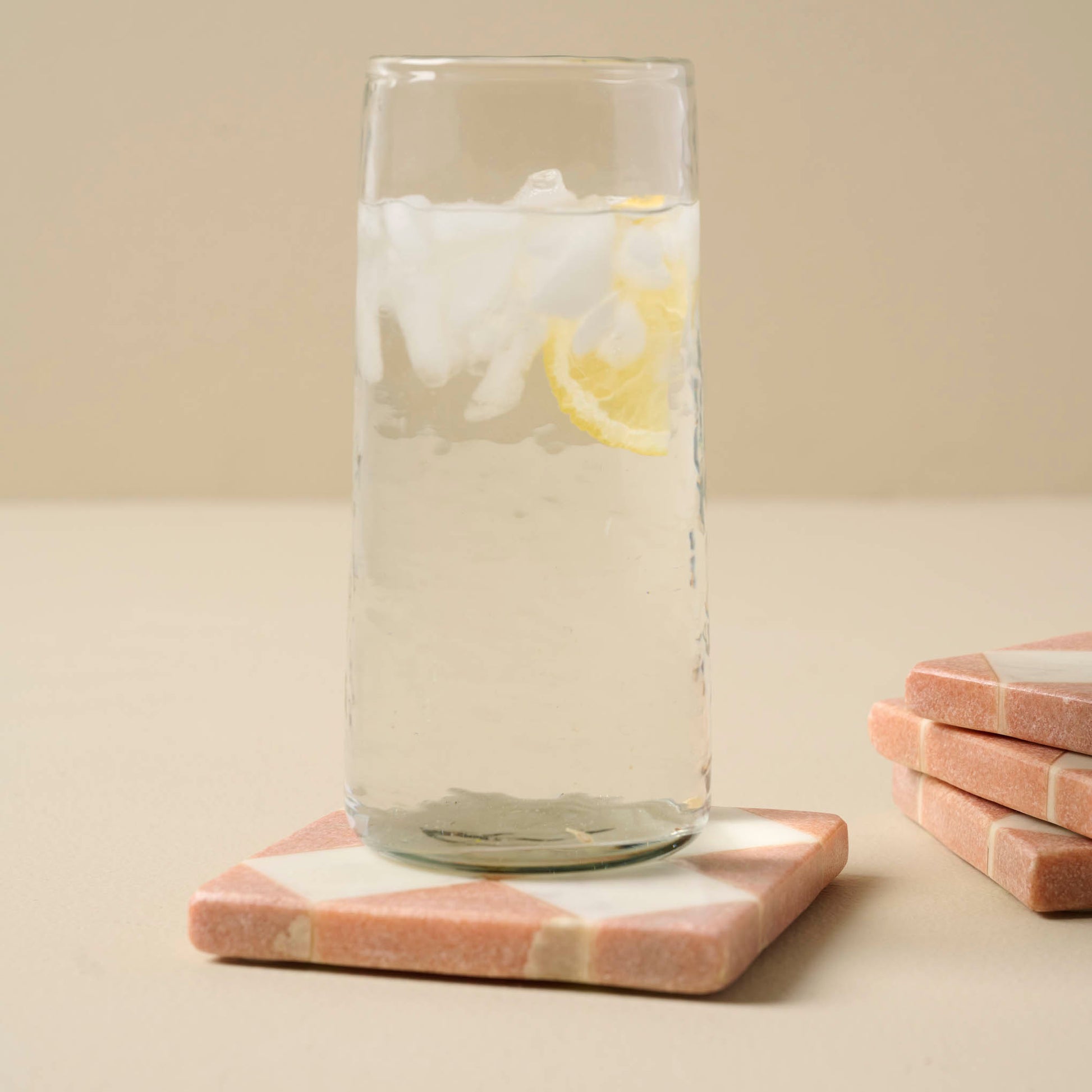 Carmella Checkered Marble Coasters Set of Four with a glass of water