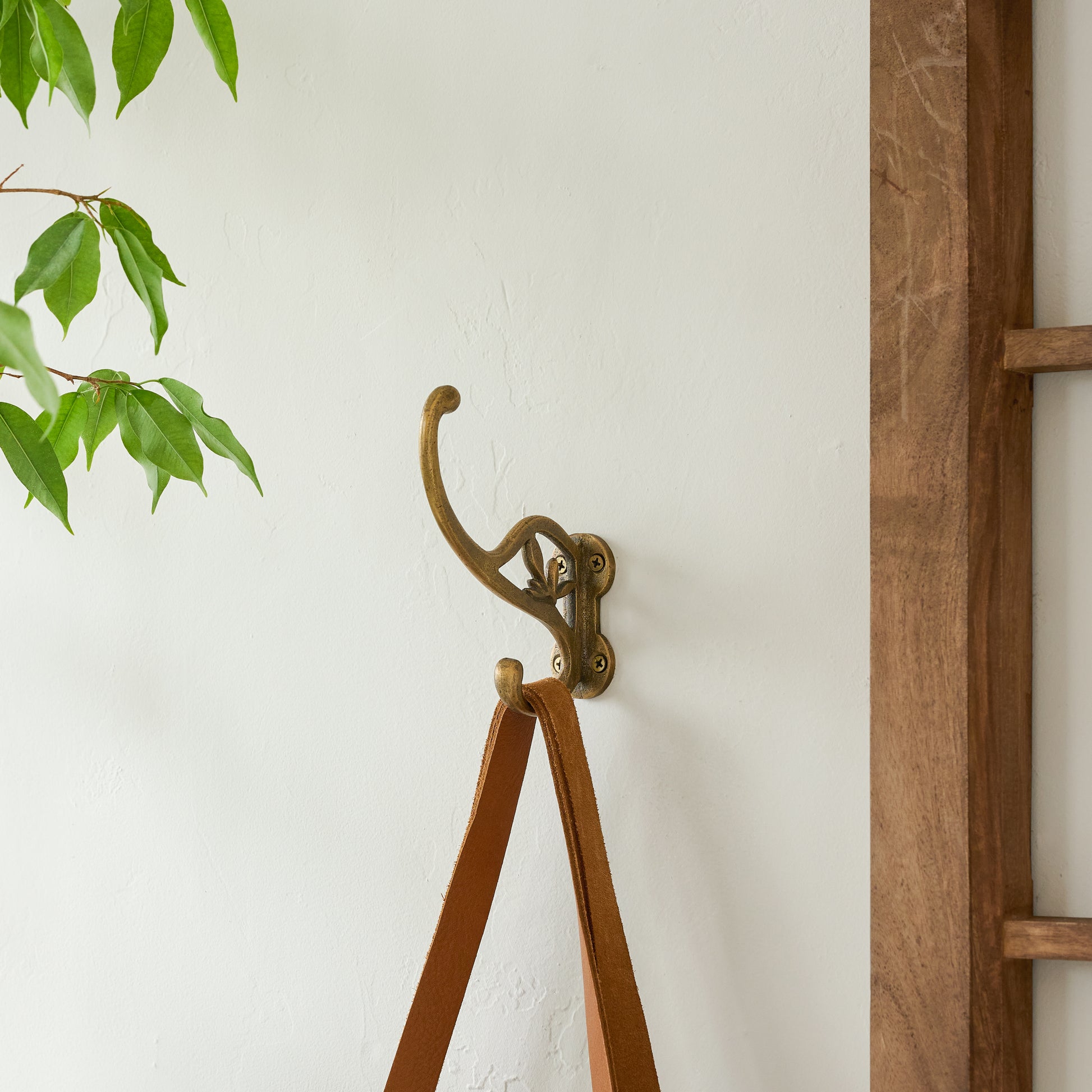 Antique Brass Floral Hook holding a leather strap