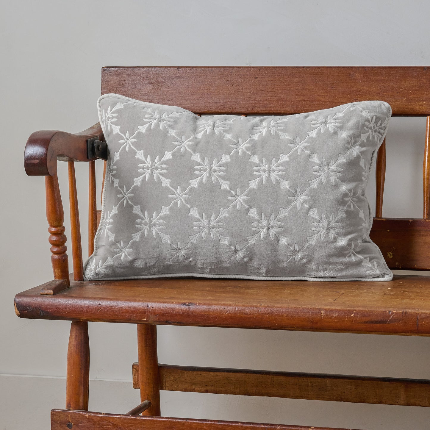 Aurora Embroidered Velvet Lumbar Pillow shown on bench