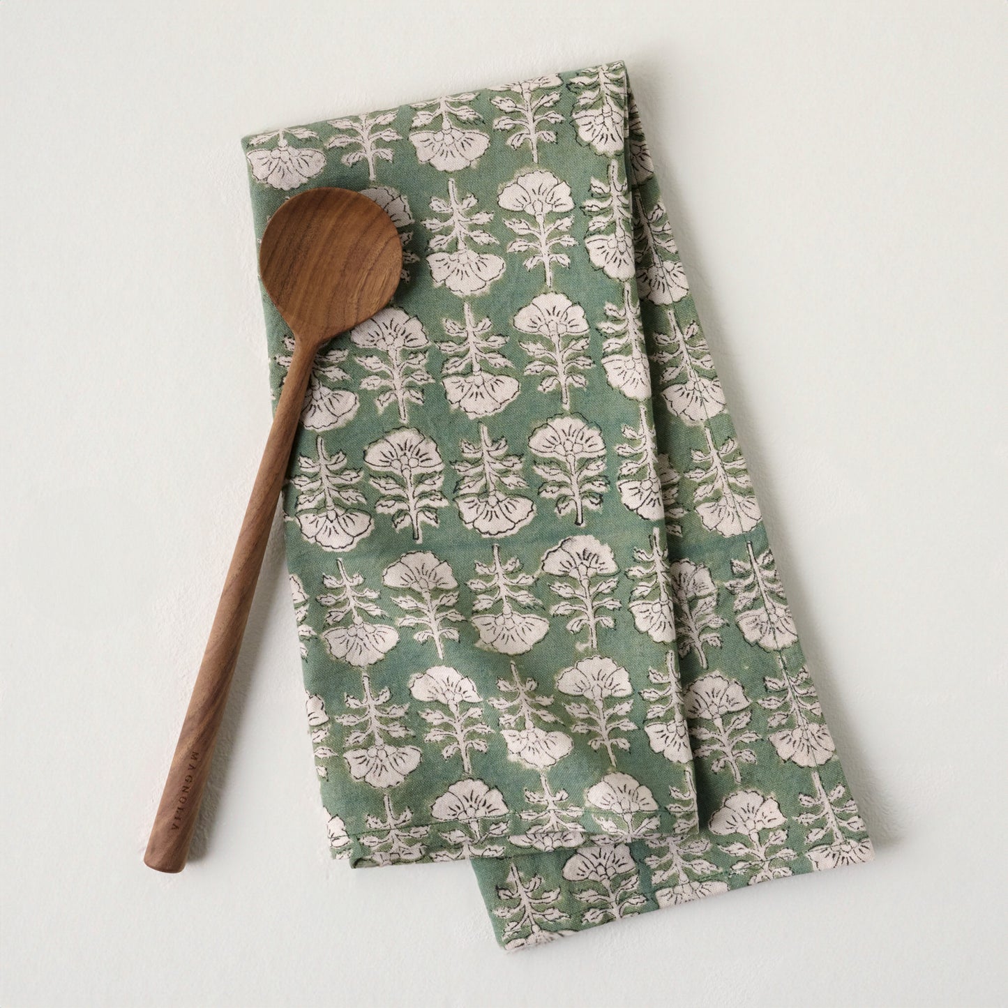 Flora Dusty Green Printed Tea Towel shown with wooden spoon