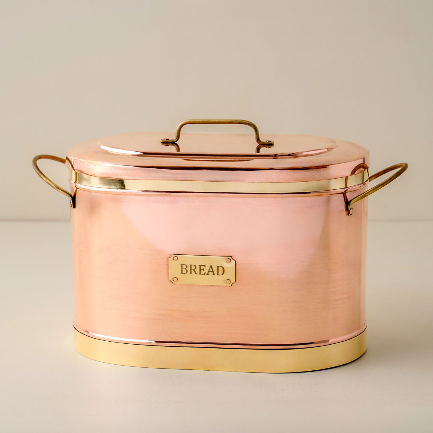 Copper bread bin with gold accents on a light background