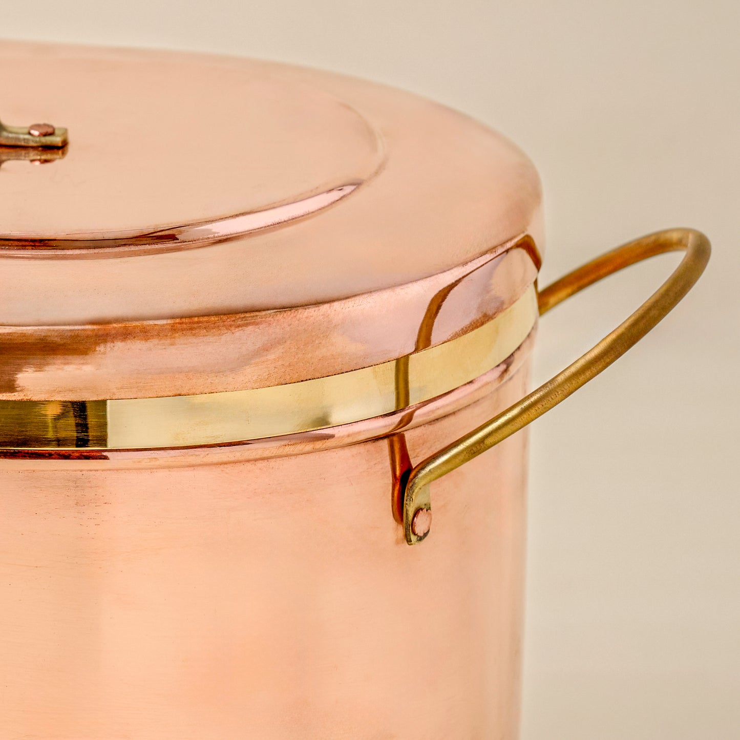 Close-up of a copper bread box with brass handle and trim on a beige background