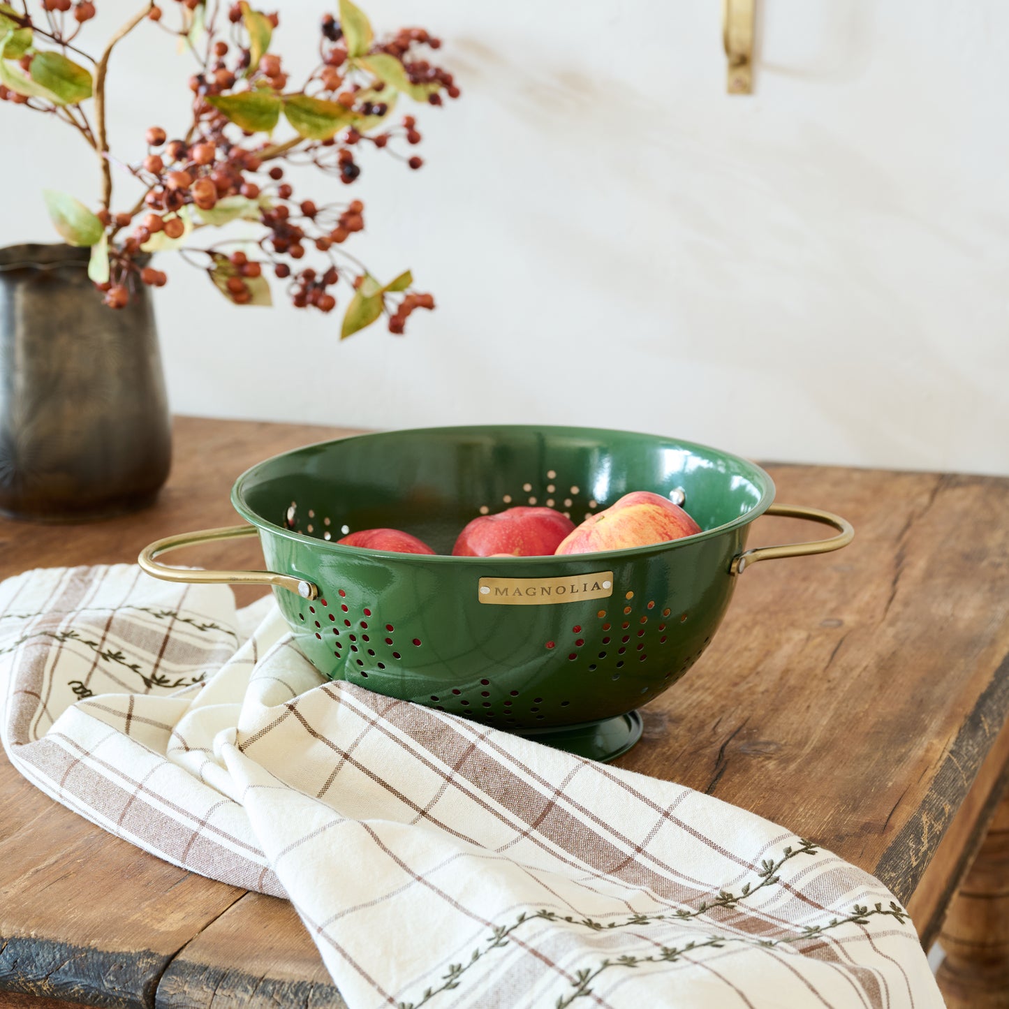 Magnolia Laurel Green Colander shown with fruit and tea towel