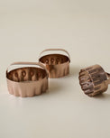 Three copper biscuit cutters on a beige background