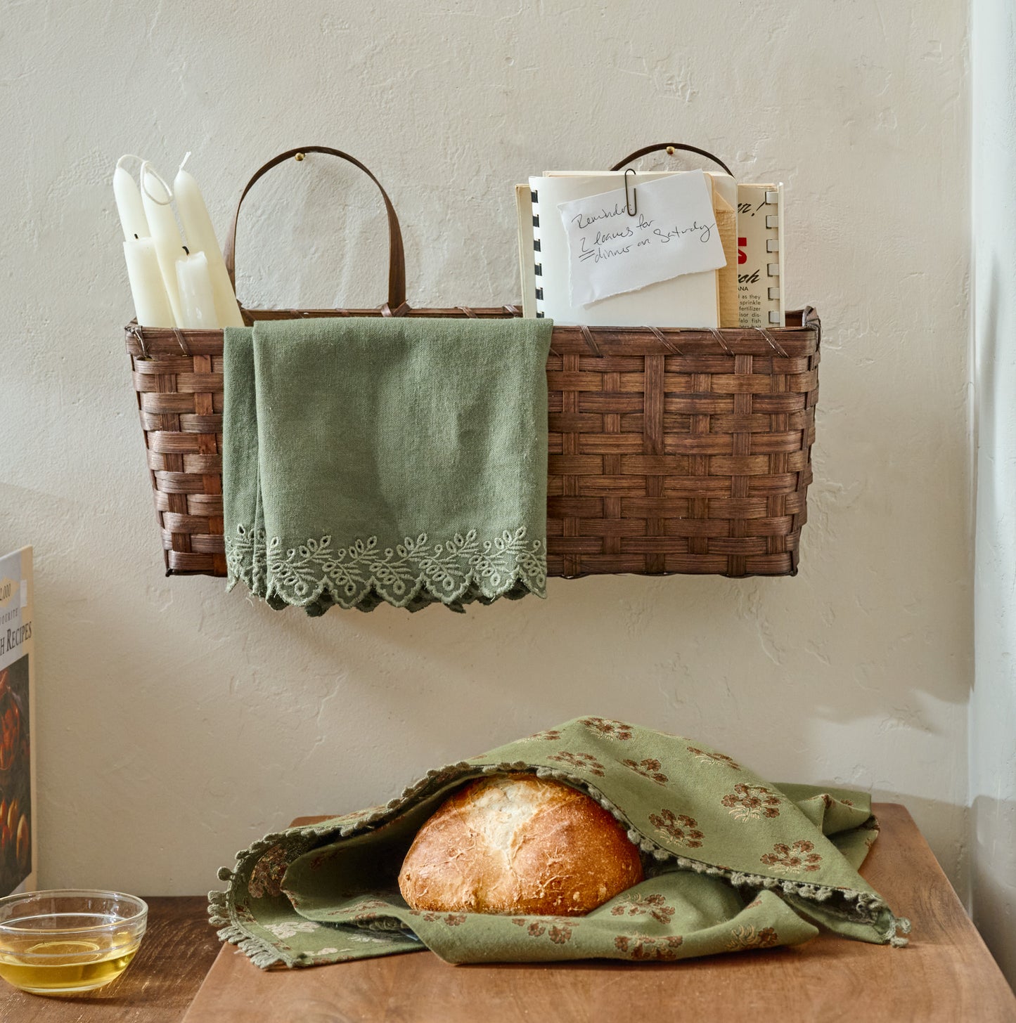 Magnolia Embroidered Scalloped Edge Tea Towel shown in basket on wall