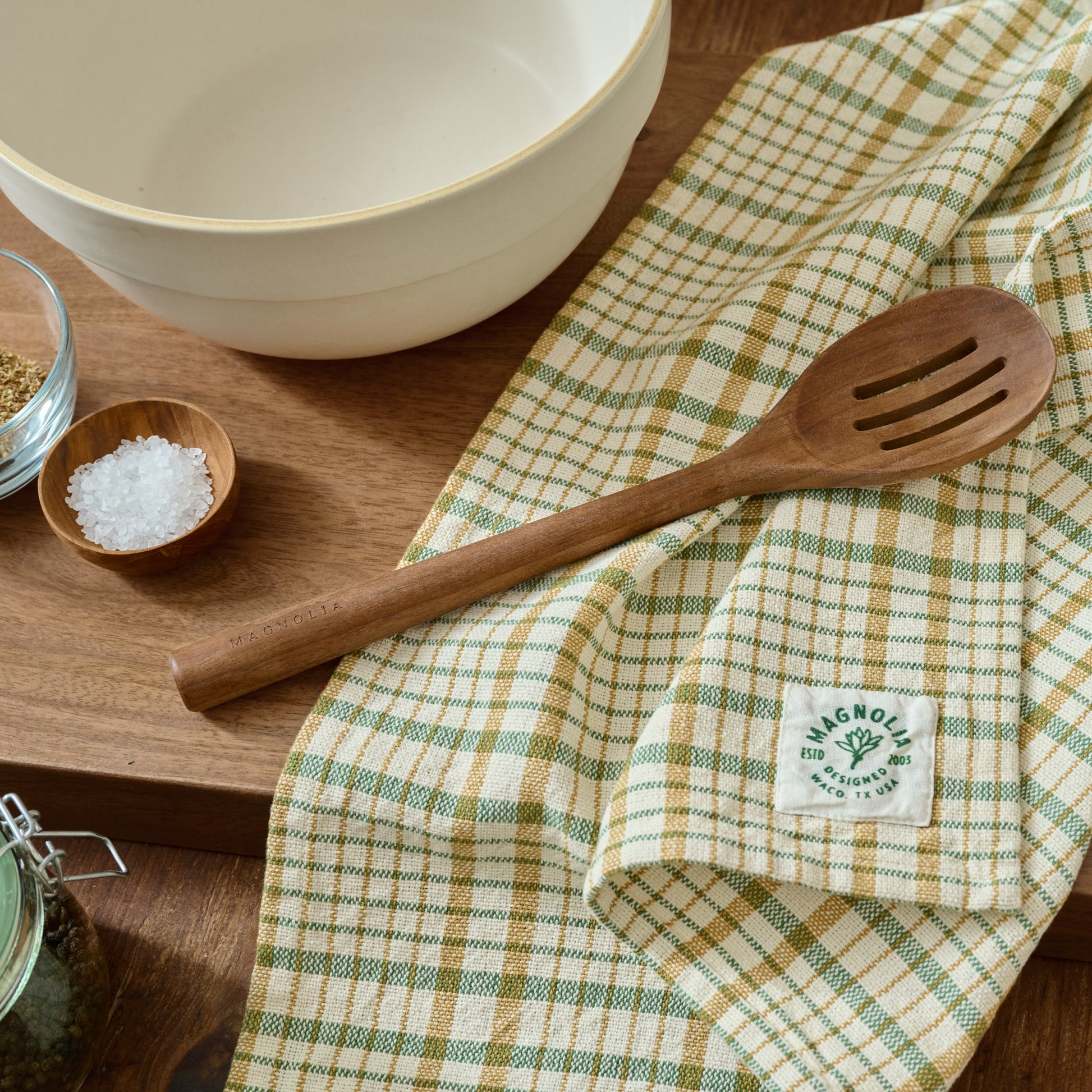 Green Windowpane Plaid Tea Towel shown on table with wooden slotted spoon