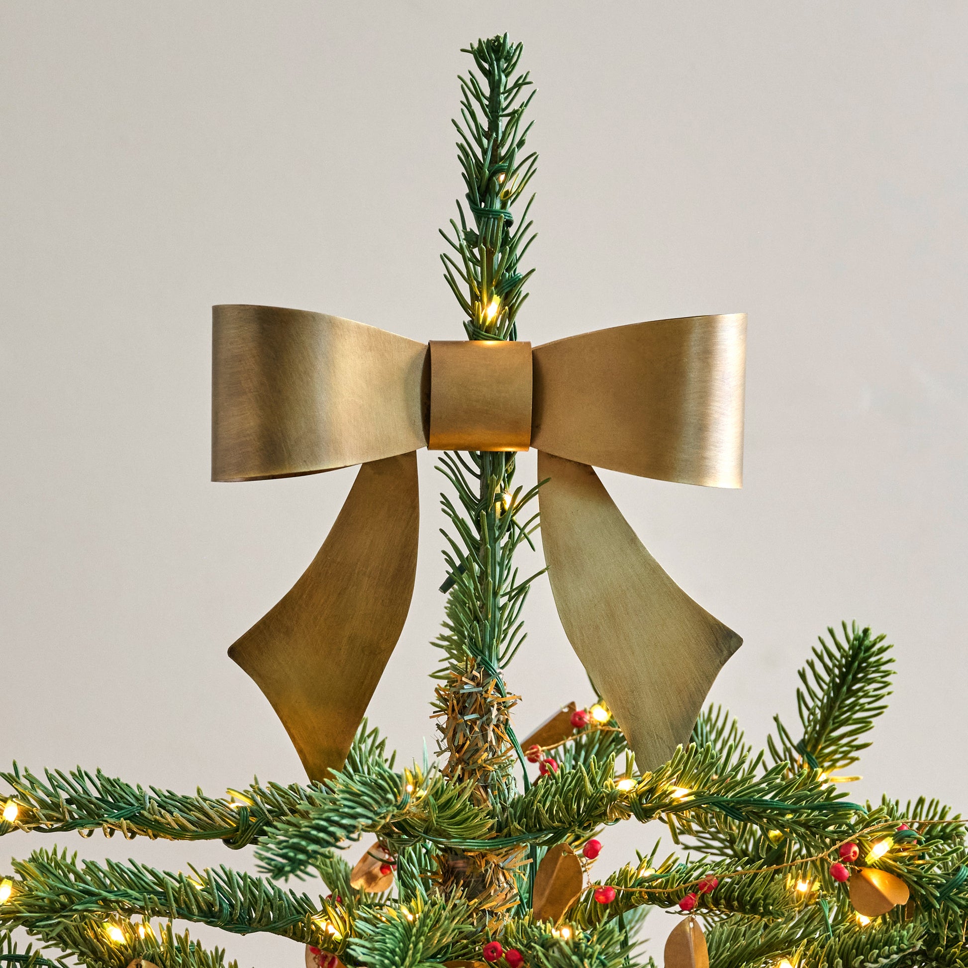 Clara Brass Bow Tree Topper shown on top of tree