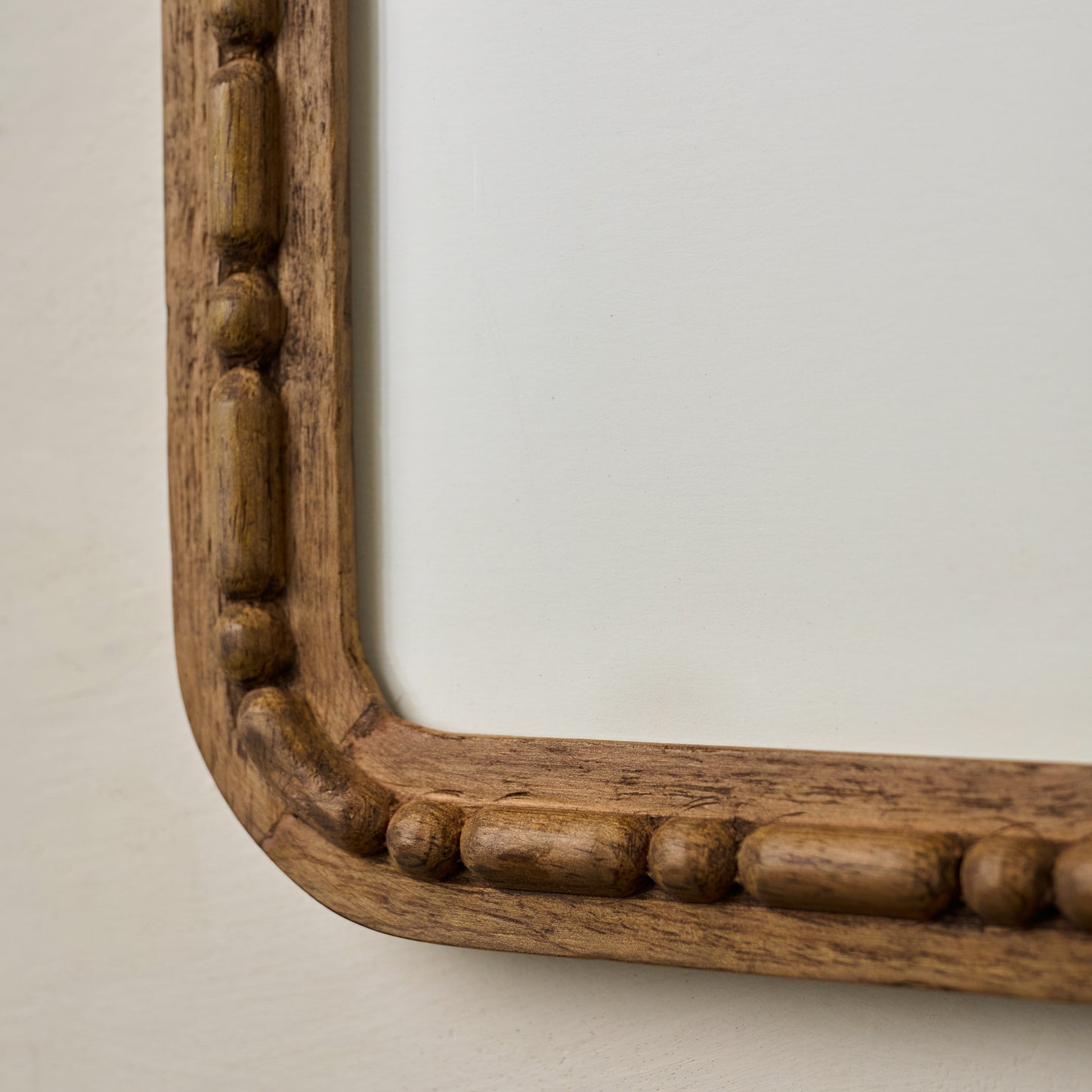 Close-up of a wooden frame with carved decorative elements on a beige background