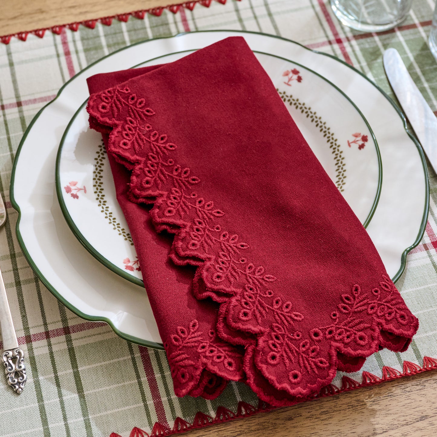 Syrah Embroidered Scalloped Edge Napkin shown folded and set on holiday place setting