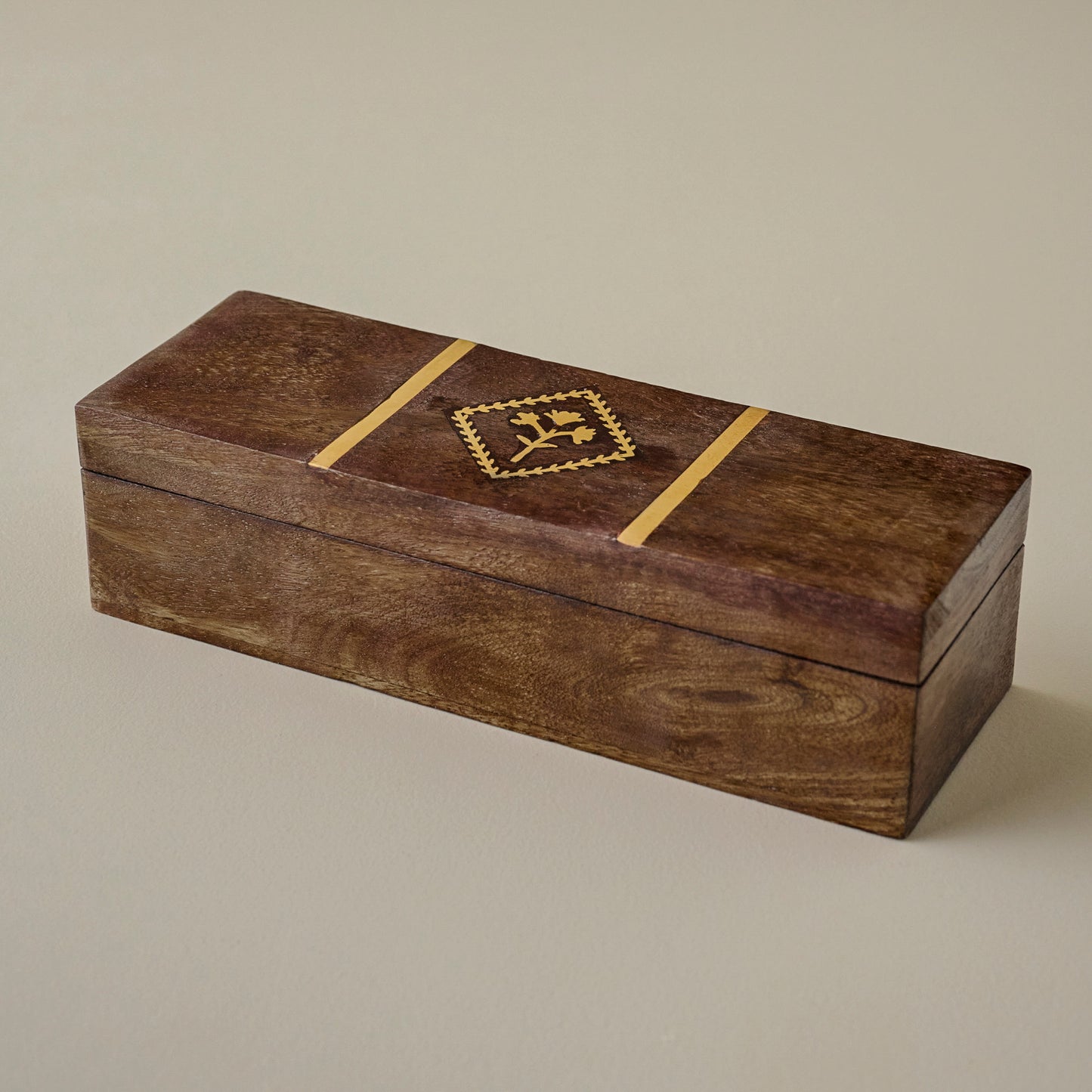 Wooden box with a decorative brass tulip emblem on a beige background