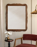 Caroline Carved Wood Mirror in a room with velvet chair and brass fluted floor lamp