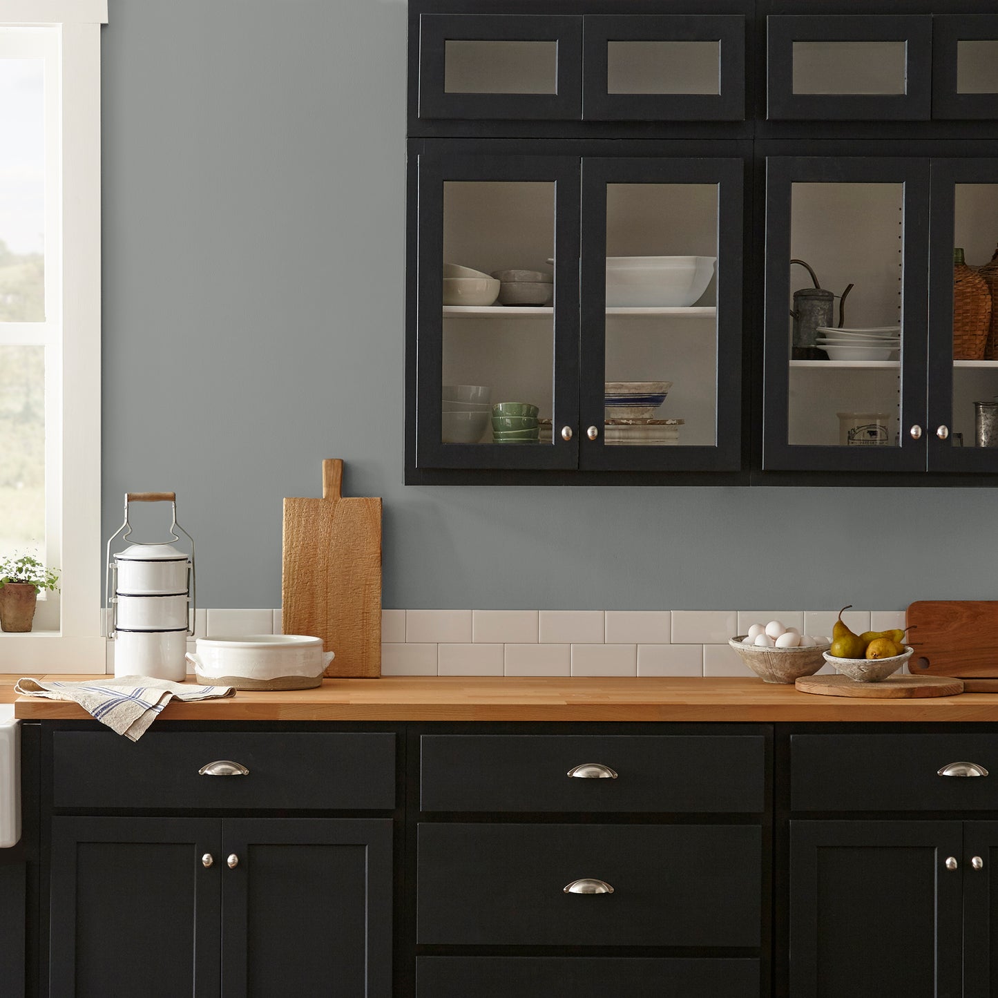 A dark gray with blue and green undertones interior paint named teak cups shown painted on kitchen wall
