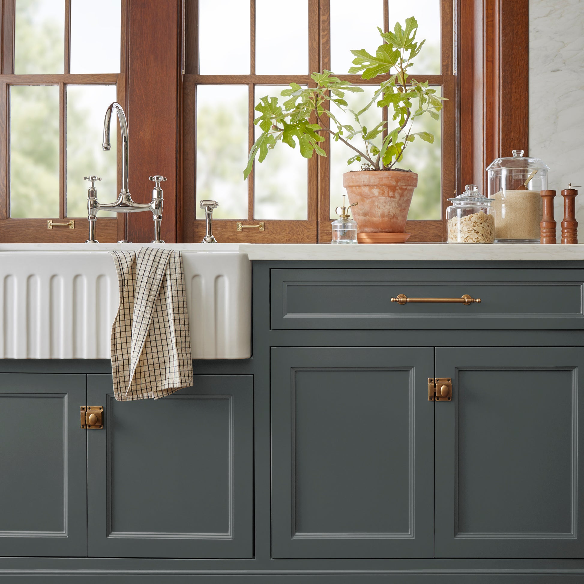 A moody navy infused with a deep green hue door and cabinet paint named cottage grove shown painted on kitchen cabinet