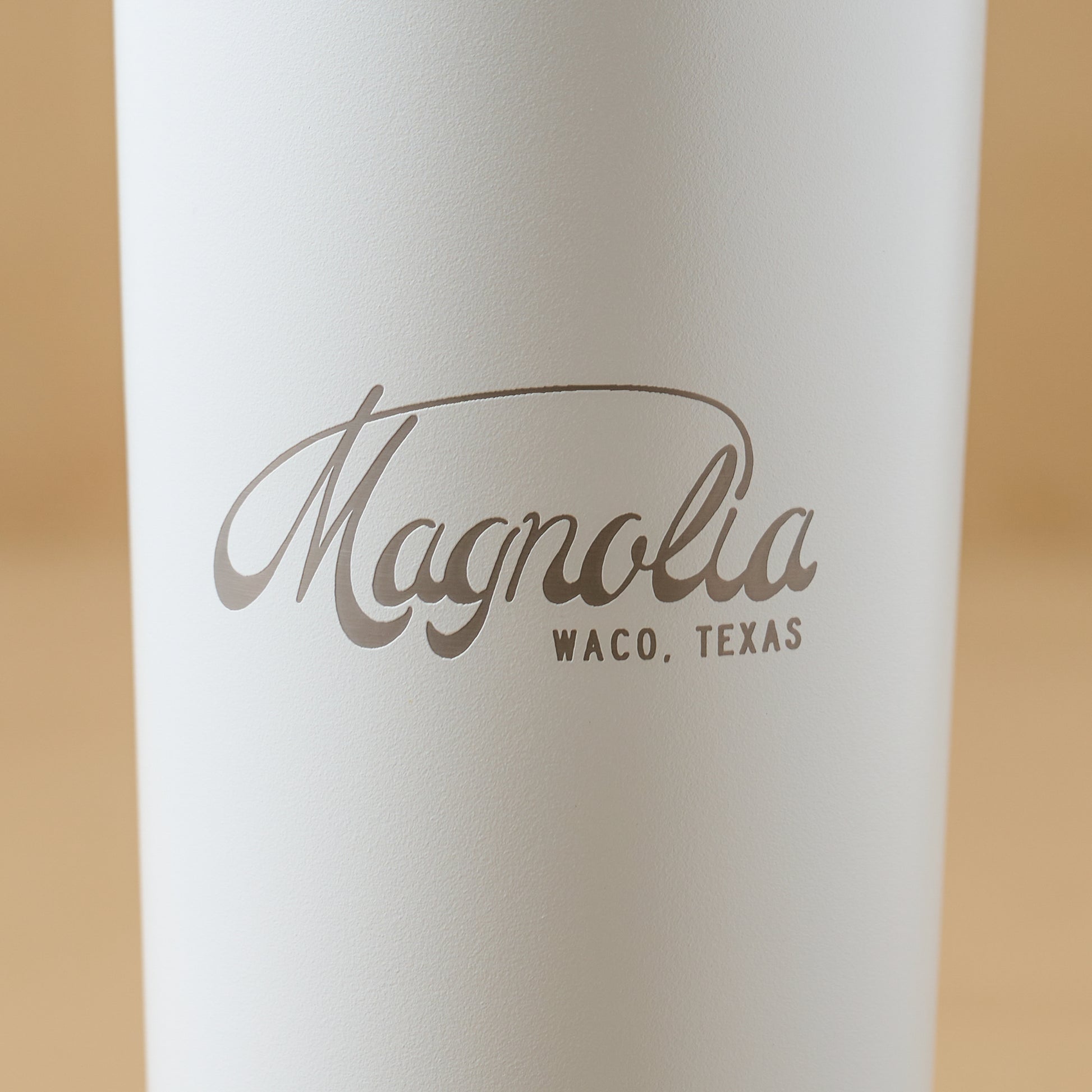 Magnolia White 24oz Cold Tumbler with Straw close up of magnolia logo on cup