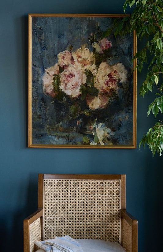 Still Life with Roses in a Glass Vase hanging on a blue wall above a chair