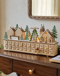 Wooden advent calendar with festive village scene on a wooden surface.