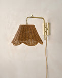 Wall-mounted lamp with wicker shade and brass arm on a beige wall