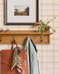 Wade Wood Wall Shelf with Hooks shown on a wall