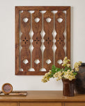 Wooden wall art with geometric pattern on a white wall, accompanied by a vase of flowers and a wooden box.