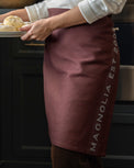 Magnolia Est. Convertible Tea Towel Apron - Brunette on a model as an apron