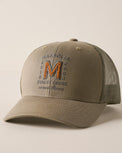 A khaki-colored trucker hat with a curved brim, featuring a mesh back and an embroidered front logo that reads 'MAGNOLIA EST. 2003 QUALITY COOLS since 2003' with a large orange 'M'.