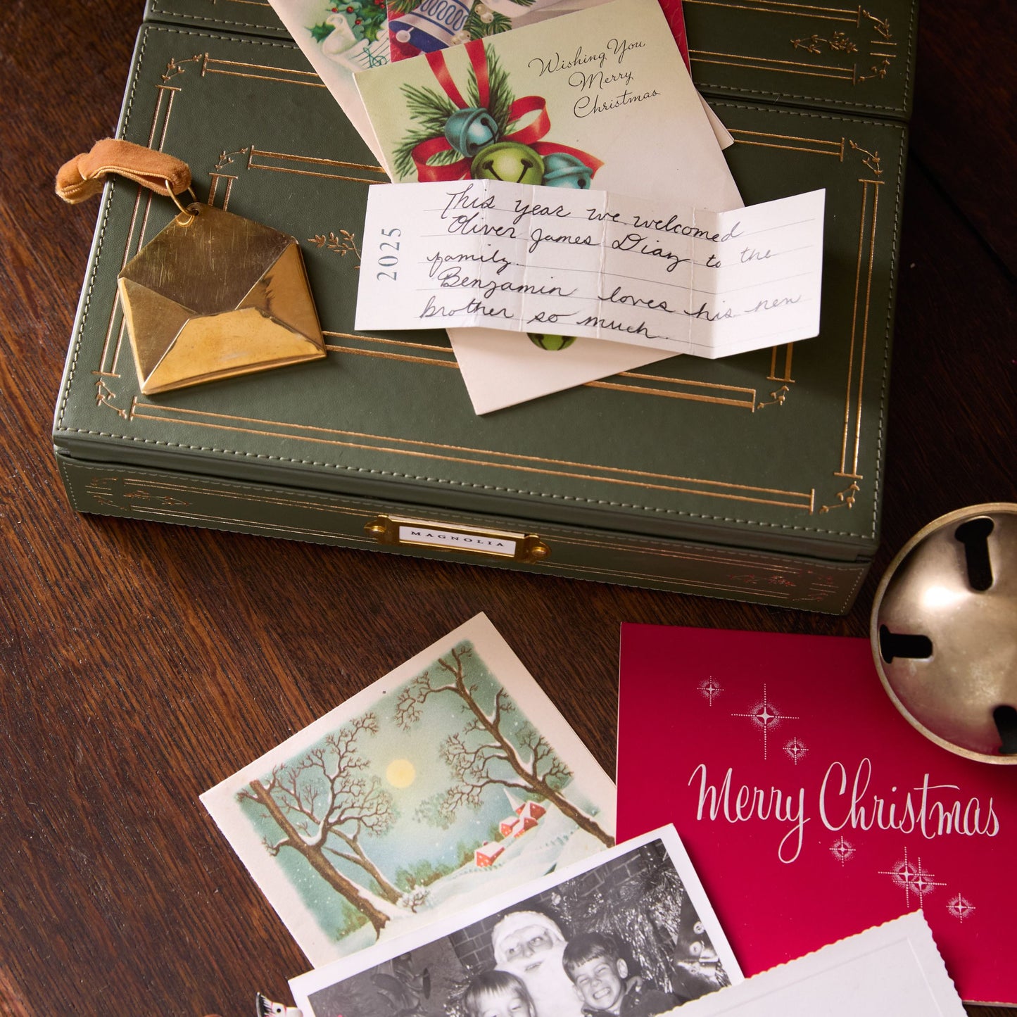 Green leather-bound memory box with Christmas cards and photos on a wooden surface