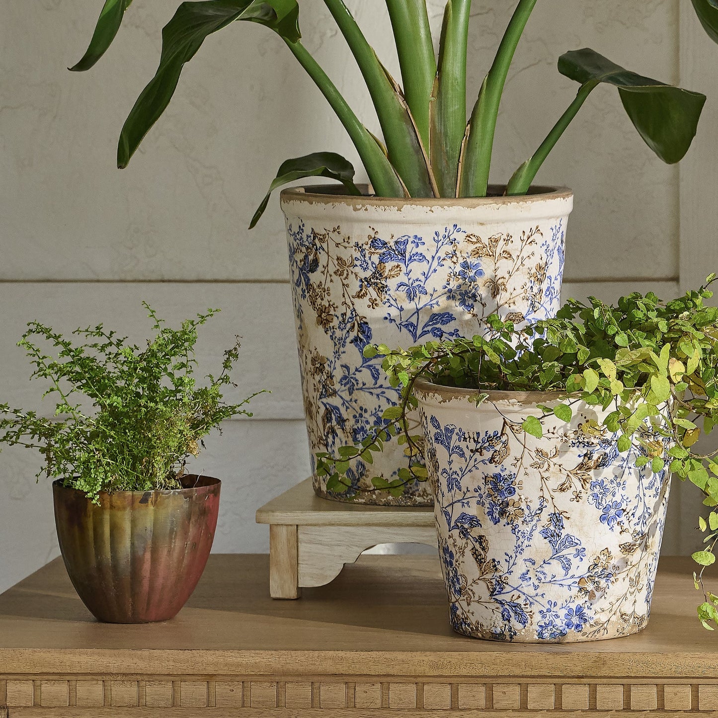 Aged Copper Planter next to two blue and white distressed planters on table